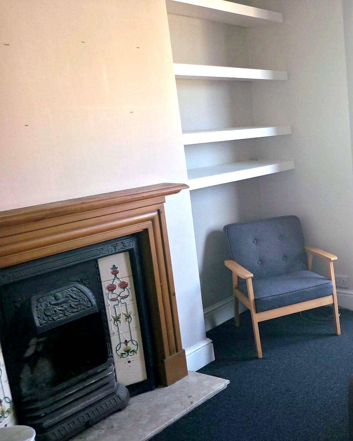 Bedroom with a period fireplace, shelves and an armchair